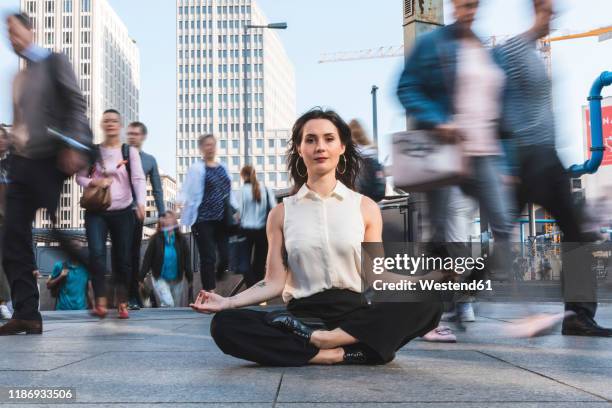 young businesswoman practising yoga in the city at rush hour, berlin, germany - hauptverkehrszeit stock-fotos und bilder