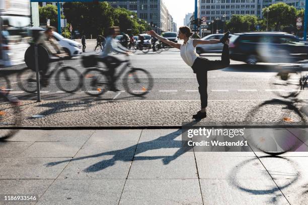 young businesswoman practising yoga in the city at rush hour, berlin, germany - yoga germany stockfoto's en -beelden