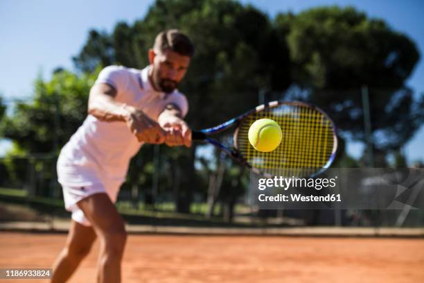 tennis player during a tennis match, focus on tennis ball - tennisschläger stock-fotos und bilder