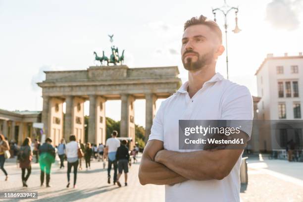 portrait of young man standing in front of brandenburger tor at backlight, berlin, germany - porta de brandemburgo imagens e fotografias de stock