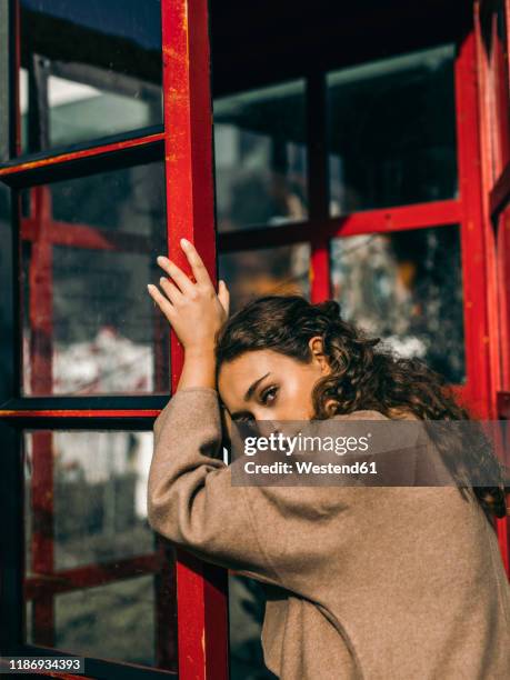 young woman leaning on a telephone box - munich autumn stock pictures, royalty-free photos & images