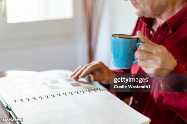 senior man looking at home at stamp collection - stamp collection stock pictures, royalty-free photos & images