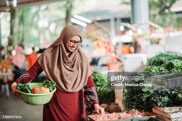 アジアの美しいマレーの女性は、彼女の腰に野菜のバスケットを保持し、朝の市場の買い物中に彼女の笑顔で唐辛子を選択 - chili woman ストックフォトと画像