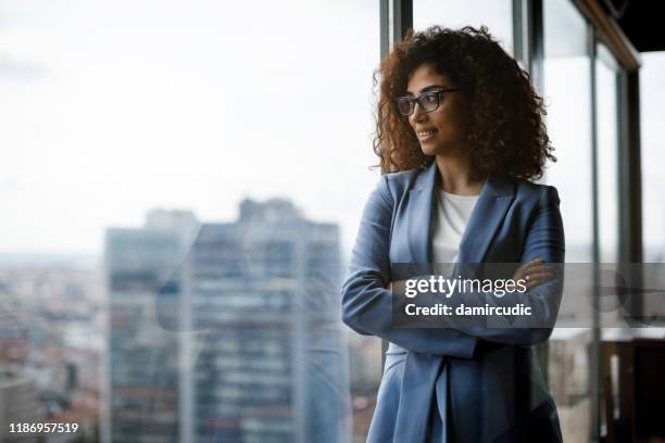 smiling thoughtful businesswoman looking through window - asset manager stock pictures, royalty-free photos & images