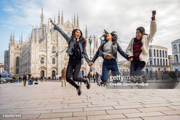 three asian women jump around the city square - milan street fashion 2019 imagens e fotografias de stock