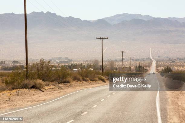 desert highway with mountain range - empty road stock-fotos und bilder