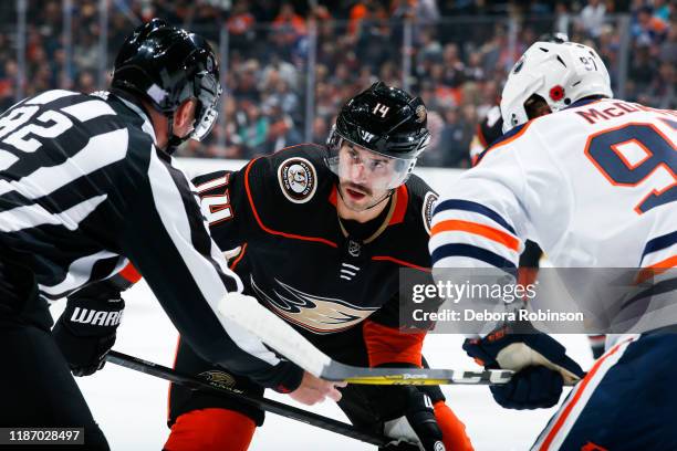 Adam Henrique of the Anaheim Ducks prepares for a face-off against Connor McDavid of the Edmonton Oilers with linesman Mark Shewchyk dropping the...