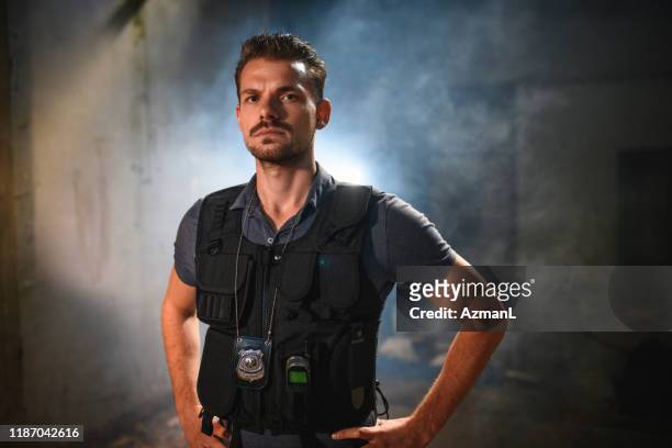 stern caucasian male police officer at nighttime crime scene - detective stock pictures, royalty-free photos & images