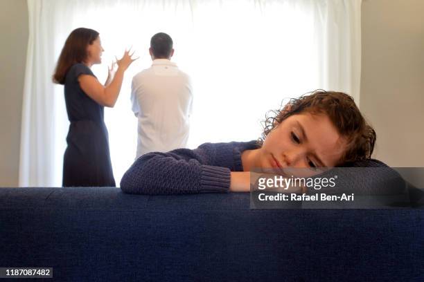 young girl is upset as parents fight behind her - children divorce stock-fotos und bilder