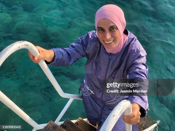 woman with wearing burqini on sea pier - muslim woman beach stock-fotos und bilder