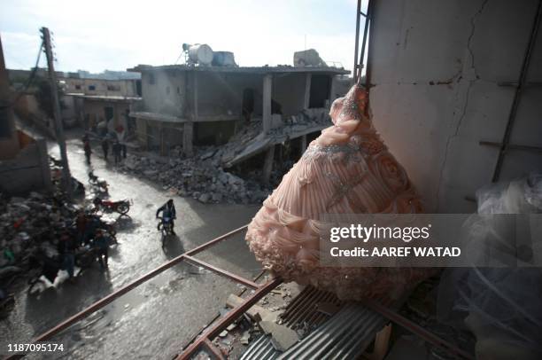 Wedding dress is seen in the destroyed window of a bridal shop in a damaged building in Balyun in Syria's northwestern Idlib province, on December 8...