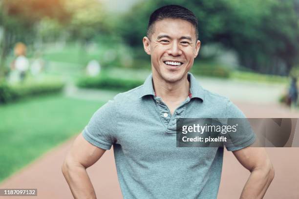 portrait of a smiling man in the park - mid adult men stock pictures, royalty-free photos & images