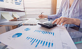 Business person working on financial report and analyzing revenue and expenses data with calculator in office