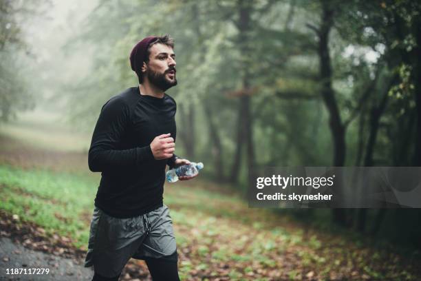 jonge atletische man loopt in de herfst dag in het park. - runner man stockfoto's en -beelden