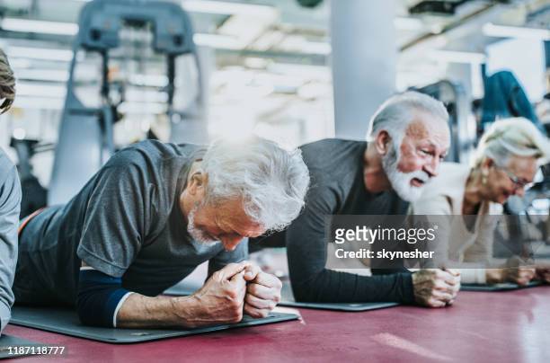 group of active seniors exercising strength in plank position in a health club. - practicing stock pictures, royalty-free photos & images