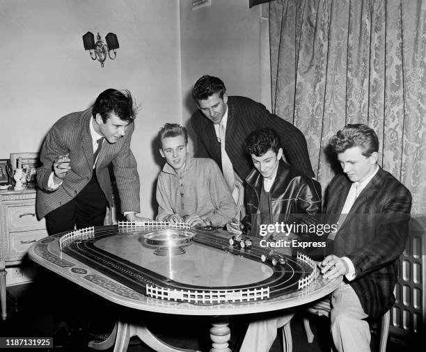 British rock and roll singers Marty Wilde, Billy Fury , Vince Eager, Dickie Pride , and Kenny Packwood playing with a toy car track, UK, 12th...