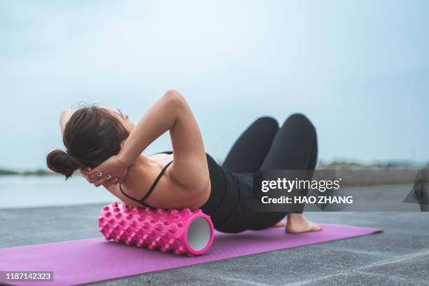 asian woman pilates instructor stretching and warming up using foam rolle - asian latex fotografías e imágenes de stock
