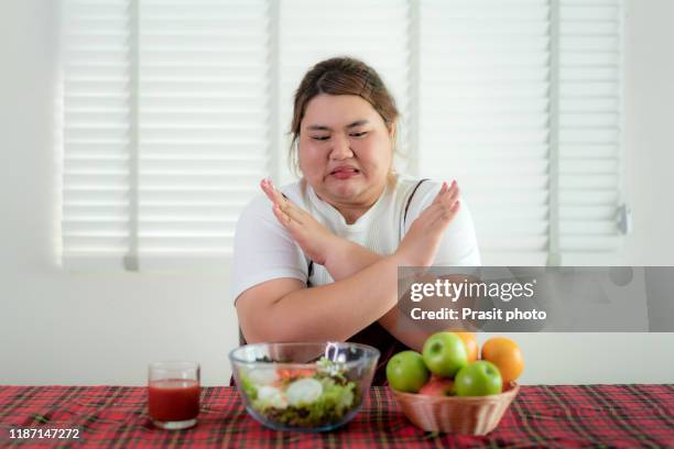 asian overweight woman bored emotion and refuse for eating fresh green vegetables salad on table for good health at home, nutrition, weight loss, lifestyle, healthy food and dieting concept - fat asian woman stock-fotos und bilder