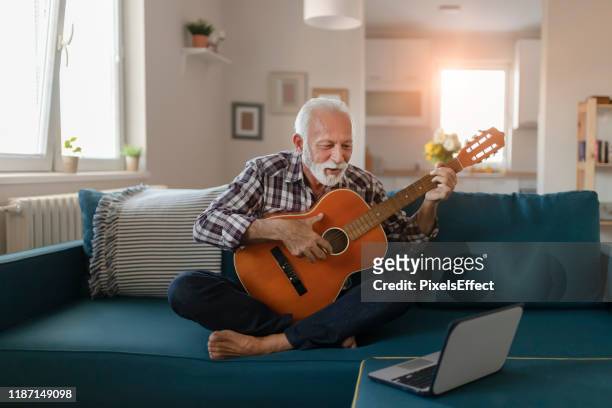 senior man leert akoestische gitaar online spelen - zingende man stockfoto's en -beelden
