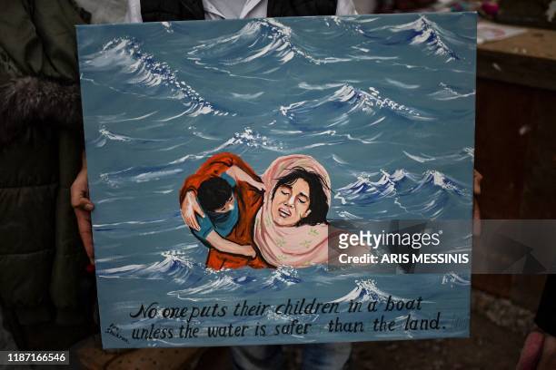 Shukran, a 38-year-old man from Afghanistan, holds one of his paintings inside his makeshift atelier in the overcrowded Moria camp in Lesbos on...