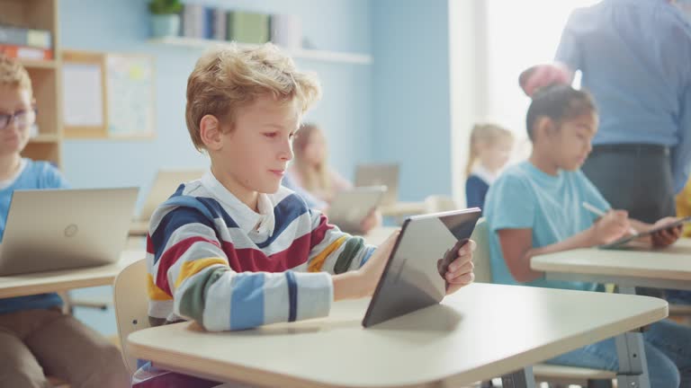 https://media.gettyimages.com/id/1187169292/video/elementary-school-computer-science-class-cute-boy-uses-digital-tablet-computer-his-classmates.jpg?b=1&s=640x640&k=20&c=1tDVv-VIsO9Ls4svjf1j8VZaihf95KD1UpsZJCpyau0=