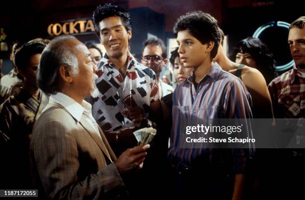 View of, fore from left, American actors Pat Morita , Yuji Okumoto , and Ralph Macchio in a scene from the film 'The Karate Kid Part II' , 1986.