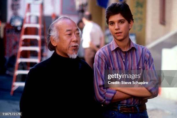 American actors Pat Morita and Ralph Macchio talk on the set of the film 'The Karate Kid Part II' , 1986.