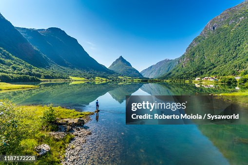 Man on water's edge admiring a Norwegian fjord, Nordfjord, Sogn og Fjordane county, Norway Man on water's edge admiring a Norwegian fjord, Nordfjord, Sogn og Fjordane county, Norway