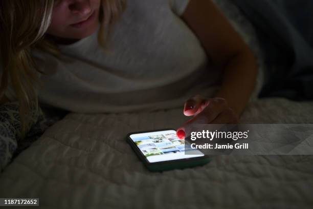 woman scrolling through social media on smart phone at night - scroll stock pictures, royalty-free photos & images