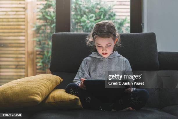 young girl using tablet on sofa - young girls homework stockfoto's en -beelden