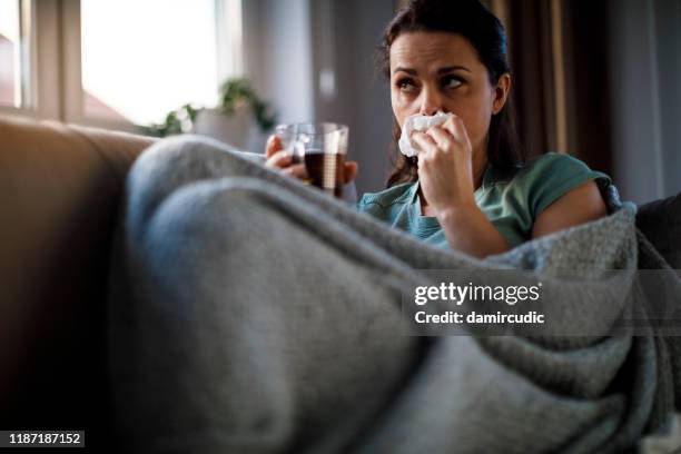 sick woman lying in bed and blowing nose - caucasian woman sick in bed coughing stock pictures, royalty-free photos & images
