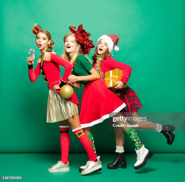 tanzende teenager-mädchen tragen weihnachtskleidung vor grünem hintergrund - christmas funny stock-fotos und bilder