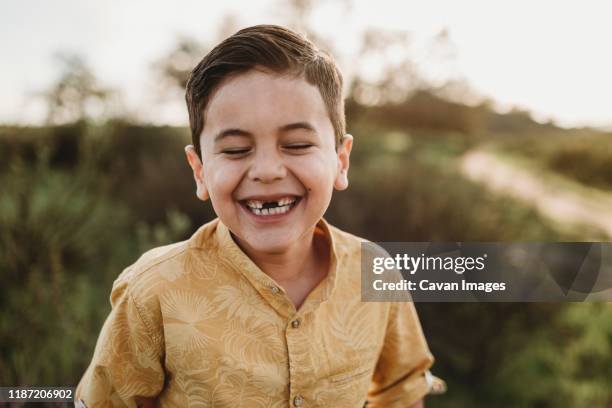 portrait of school-aged boy missing two front teeth with eyes closed - kid missing teeth stock pictures, royalty-free photos & images