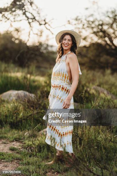 full length portrait of young woman smiling in dress in backlit field - mexican american stock pictures, royalty-free photos & images