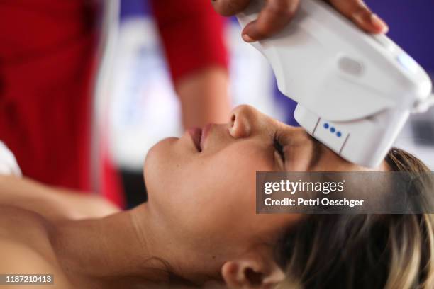 a young woman receiving a new age beauty treatment - beauty treatment stock pictures, royalty-free photos & images
