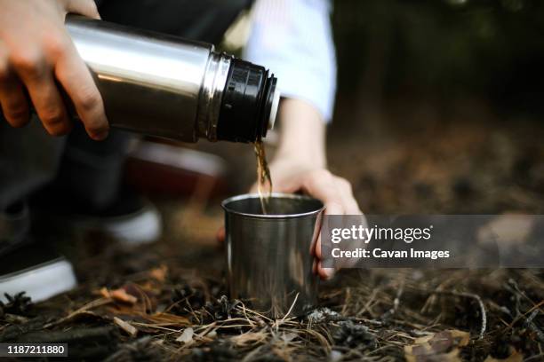 close-up of woman pouring tea from insulated drink container int - insulated drink container foto e immagini stock