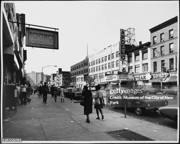 View of pedestrians walking on the sidewalk with the Apollo Theater across the street at 253 West 125th Street, New York, New York, circa 1978. It...