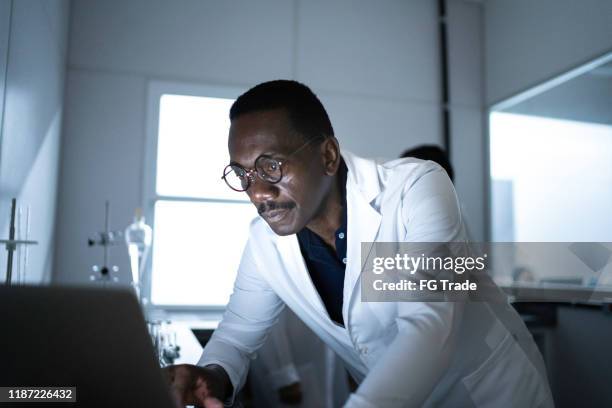 serious scientist using computer in laboratory - dedication stock pictures, royalty-free photos & images
