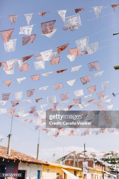 red and white paper garlands / papel tirado in strung up between houses - état du michoacan photos et images de collection