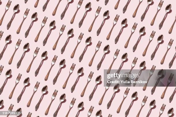 repeated spoon and fork on the pink background - bestek stockfoto's en -beelden