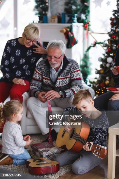 niño tocando la guitarra para sus abuelos en navidad - 12 days of christmas fotografías e imágenes de stock