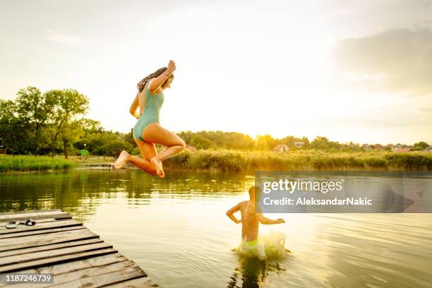 the never ending summer - group-of-friends-jumping-off-dock-into-lake stock pictures, royalty-free photos & images