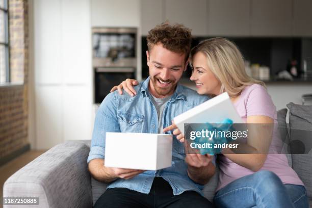 glücklicher mann öffnet sein geburtstagsgeschenk - geburtstagsgeschenk stock-fotos und bilder