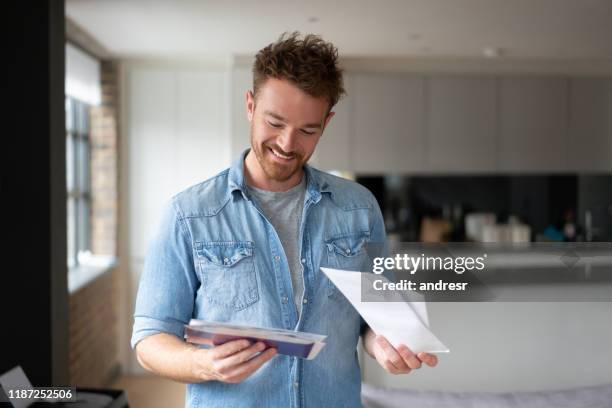 hombre feliz en casa revisando el correo - invoice fotografías e imágenes de stock