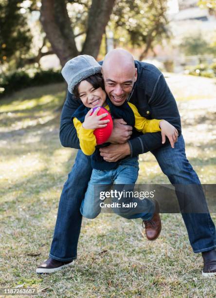 hispanic boy and father playing with football - child picking up toys stock pictures, royalty-free photos & images