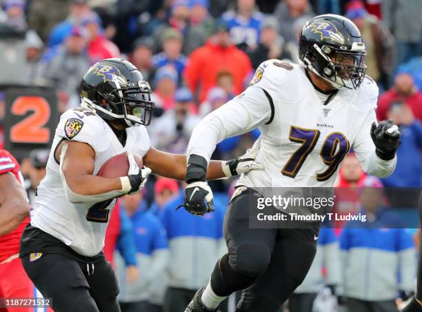 Ronnie Stanley of the Baltimore Ravens looks to make a block for Mark Ingram as he runs the ball during the second half against the Buffalo Bills at...