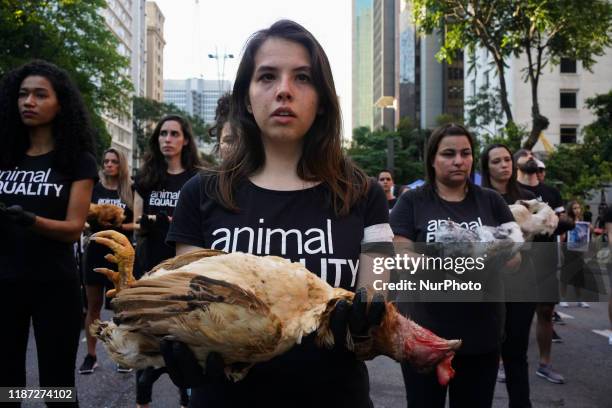 Animal rights activists from Animal Equality Brasil hold up animal carcasses, during a demonstration to protest treatment of animals and draw...