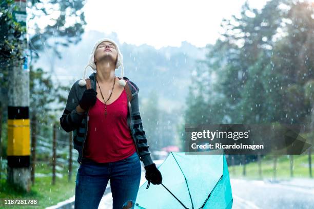 la femme apprécie la pluie qui tombe autour d'elle - se protéger de la pluie photos et images de collection