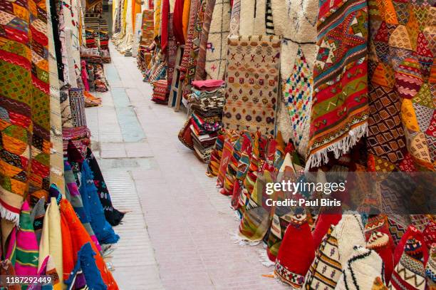 moroccan carpets bazaar. colorful carpets on sale in the narrow street of essaouira in morocco - médina photos et images de collection