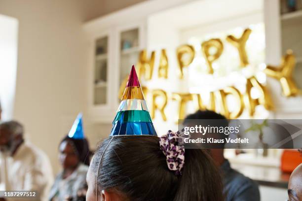 close-up of girl wearing party hat at home - kids birthday party foto e immagini stock